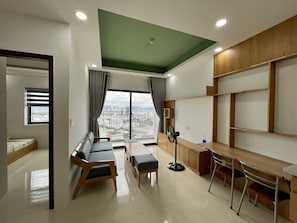Una sala moderna con un sofá, sillas, una mesa de comedor y vistas de la ciudad a través de amplios ventanales.