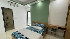 Ein Schlafzimmer mit einem Bett, einem Holztisch, einer grünen Akzentwand und einem durchgegangenen Tür sichtbaren Badezimmer.