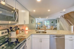 A kitchen with white cabinets, a microwave, a stove, and a sink.