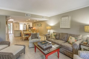 Sala de estar com sofá, cadeiras, mesa de centro e um espaço de jantar com mesa e cadeiras.