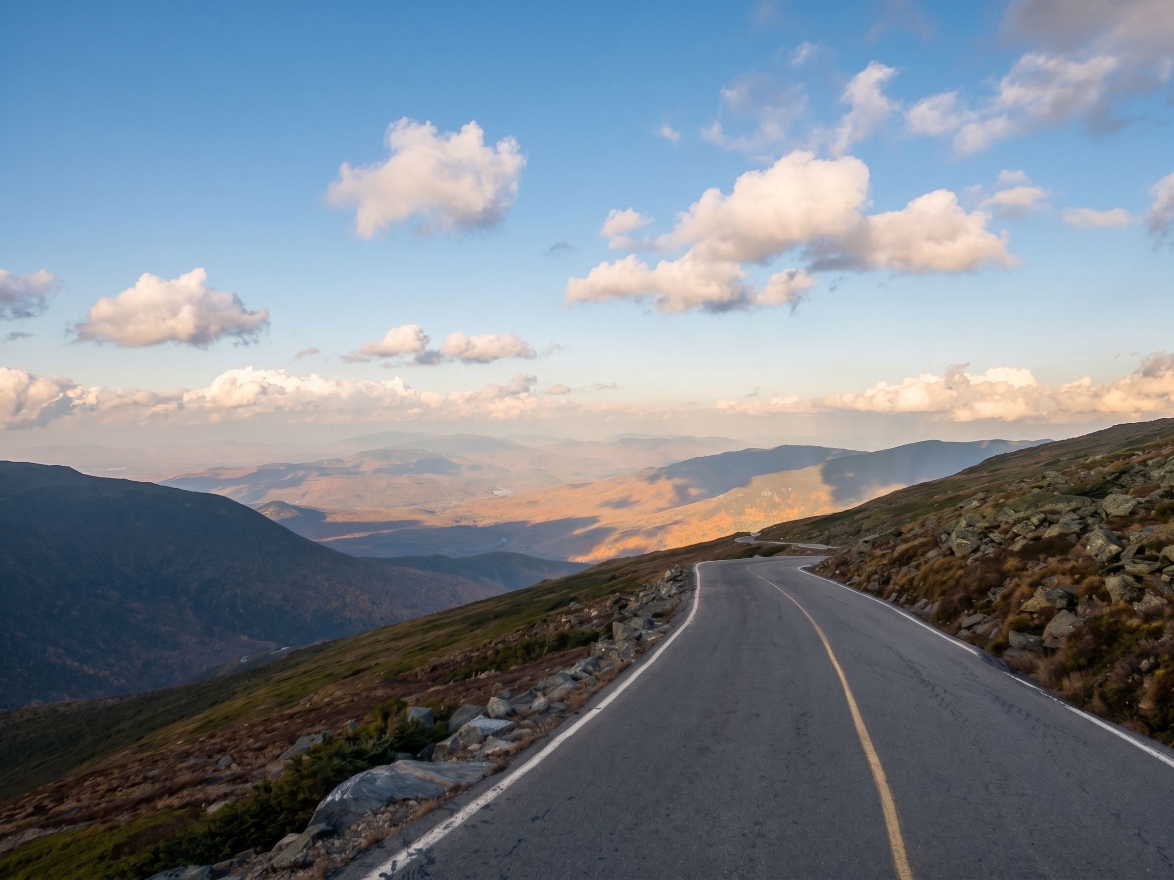 A winding mountain road with a clear sky and distant mountains.