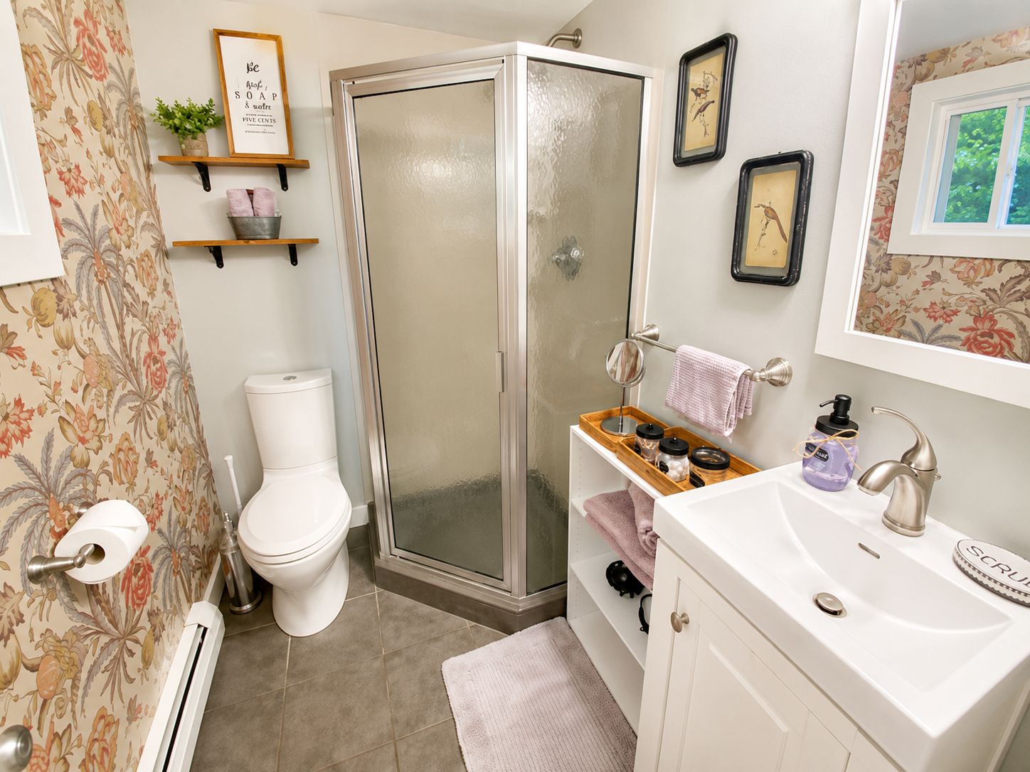 A bathroom with a toilet, shower, sink, and towel rack.