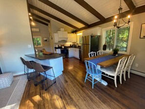 A modern kitchen with a central island, bar stools, and a dining table with chairs.