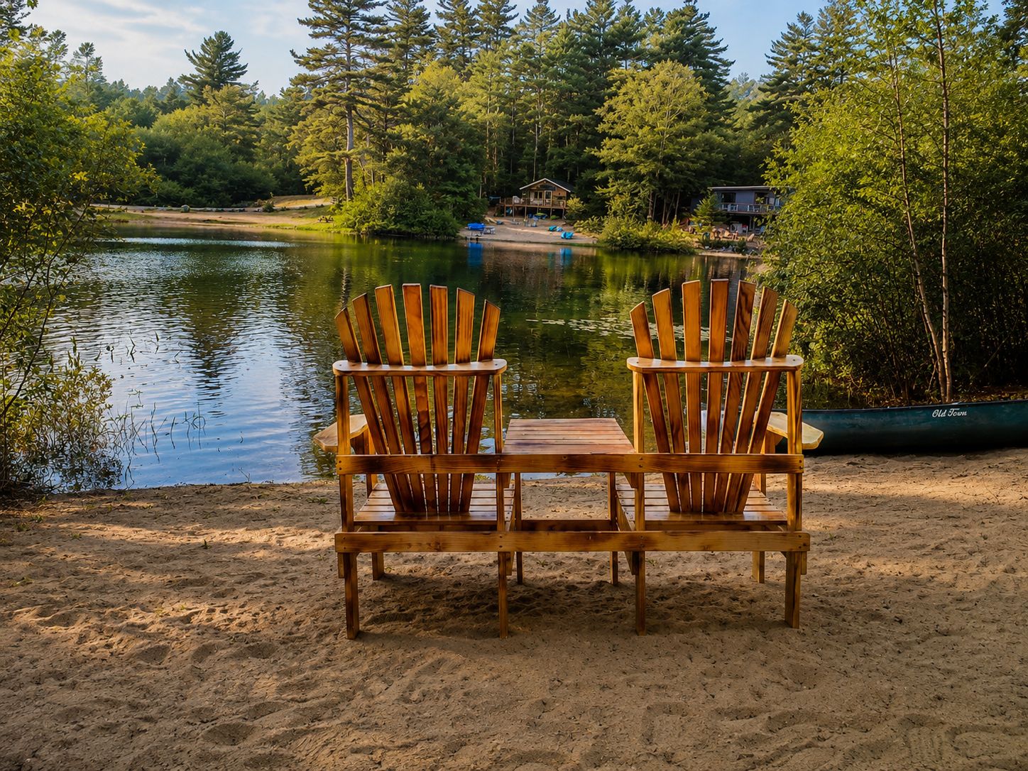 Kaksi puista Adirondack-tuolia, jotka on asetettu vastakkain järven ääreen. Taustalla näkyy laituri ja mökkejä.