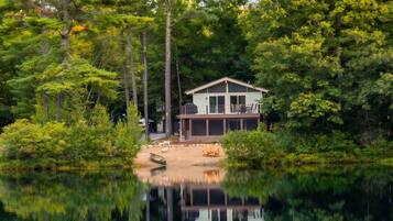 A lakeside cabin with a dock, surrounded by dense forest.