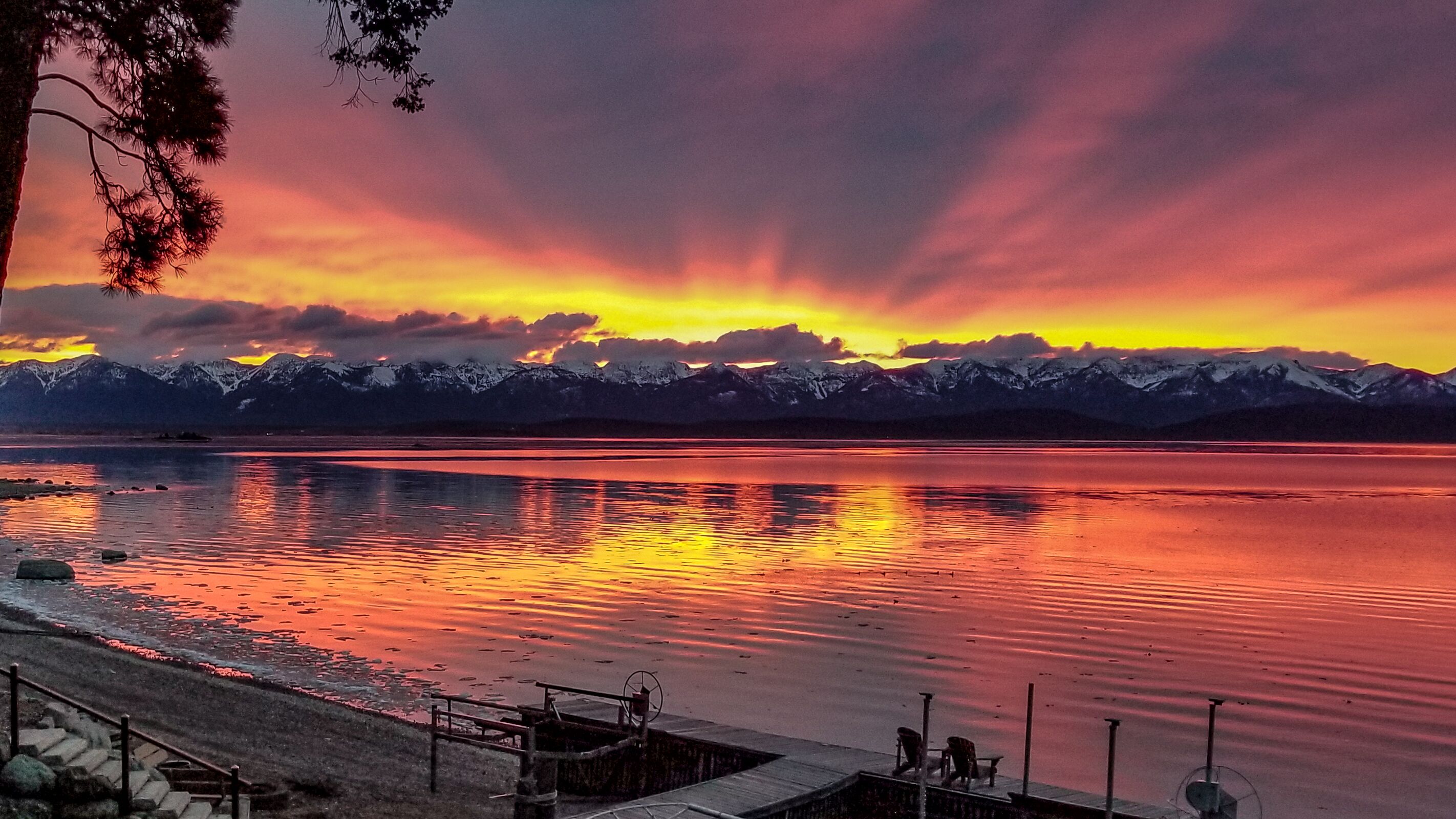A lakeside view with mountains in the background and a sunset.