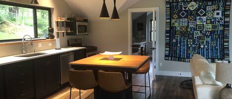 A modern kitchen with dark cabinetry, a wooden dining table, and pendant lighting.