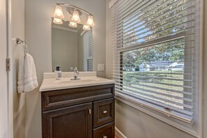 Une salle de bain avec un lavabo blanc, un meuble-lavabo en bois foncé et un grand miroir.