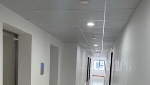 A long, narrow hallway with white walls and a tiled floor, leading to an elevator and a door at the end. - Family Apartment with Seaview Balcony 03 (Nha Trang)
