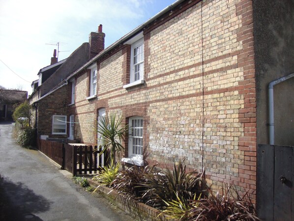 A row of terraced houses with brick walls, a wooden fence, and a pathway leading to the entrance.