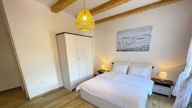 Ein Schlafzimmer mit Bett, Nachttischen, einem Kleiderschrank, einer Hängeleuchte und einem Bild an der Wand.