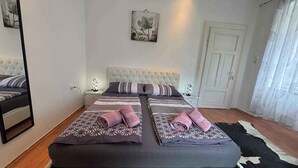 A bedroom with two beds, a mirror, a door, and a cowhide rug. - Holiday home With air conditioning in every room and a large garden with barbecue (Crikvenica)