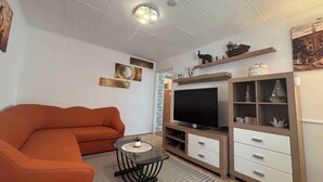 A living room with a sofa, TV, shelves, and decorative items. - Holiday home With air conditioning in every room and a large garden with barbecue (Crikvenica)