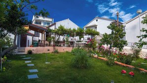 A residential area with a well-maintained garden, paved pathways, and white houses. - Holiday home With air conditioning in every room and a large garden with barbecue (Crikvenica)