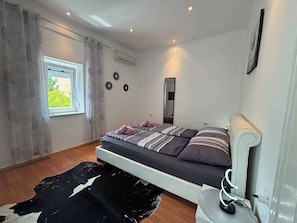 Une chambre à coucher avec un lit, une fenêtre, un climatiseur et un miroir.