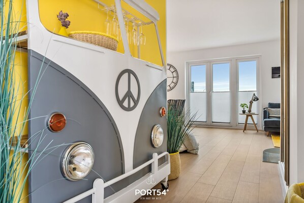 Un vehículo de estilo vintage convertido en espacio habitable con un gran ventanal, un símbolo de paz y una cesta de mimbre.