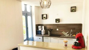 Una cocina compacta con una encimera, microondas, cafetera y un lavabo.