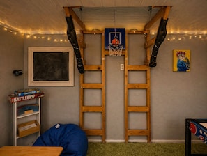 Une pièce équipée d’un panier de basket, d’échelles en bois, d’une bibliothèque et d’un fauteuil en forme de sac de haricots.