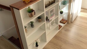 Ein weißer Holzkonsole mit mehreren Ablagen, dekoriert mit Herbstlaub, verschiedenen kleinen Pflanzen und Dekorationsobjekten.