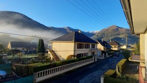 Eine Wohnstraße mit Häusern, blauem Himmel und Bergen im Hintergrund.