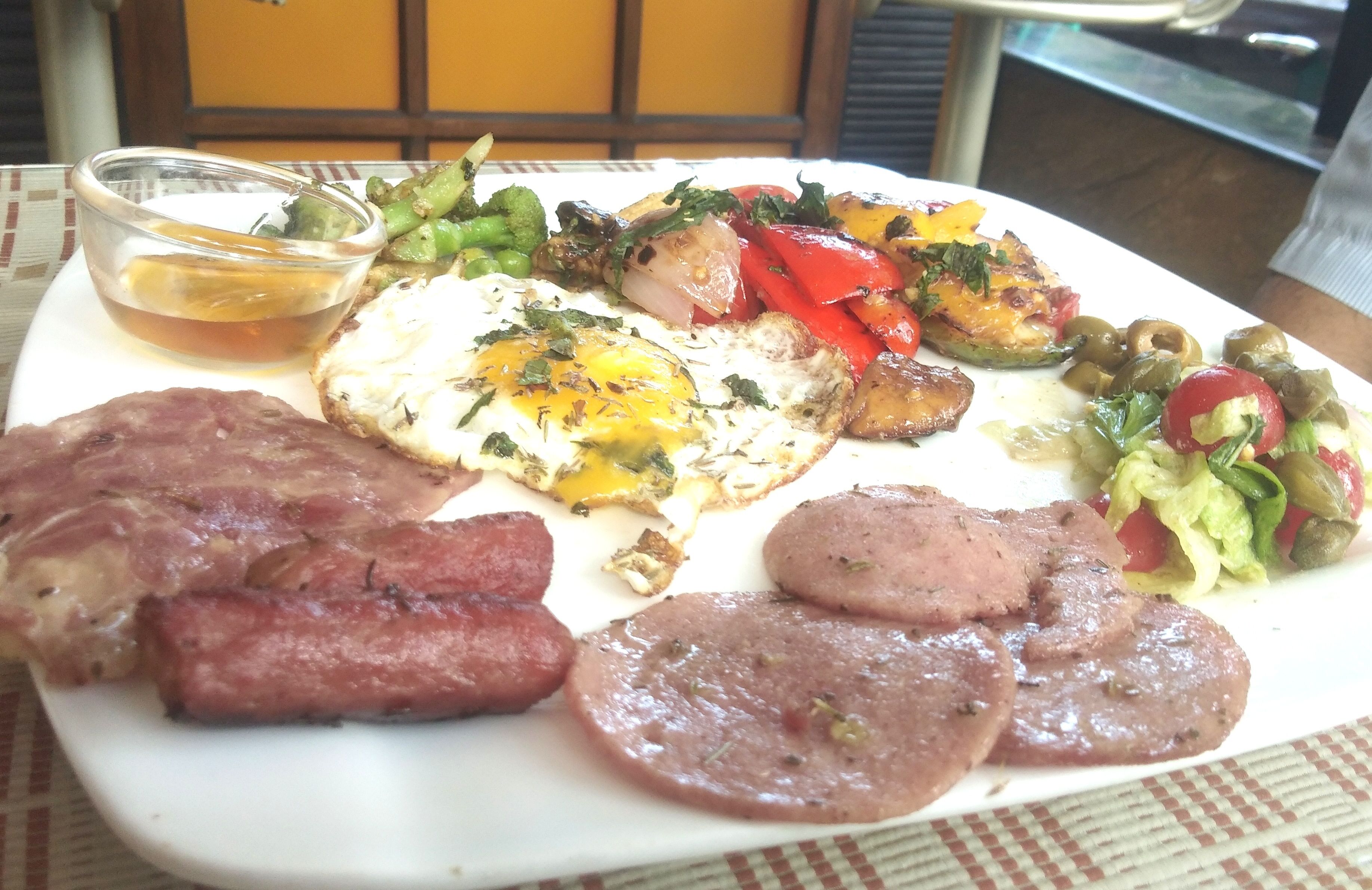 A plate of food with eggs, sausages, and vegetables.