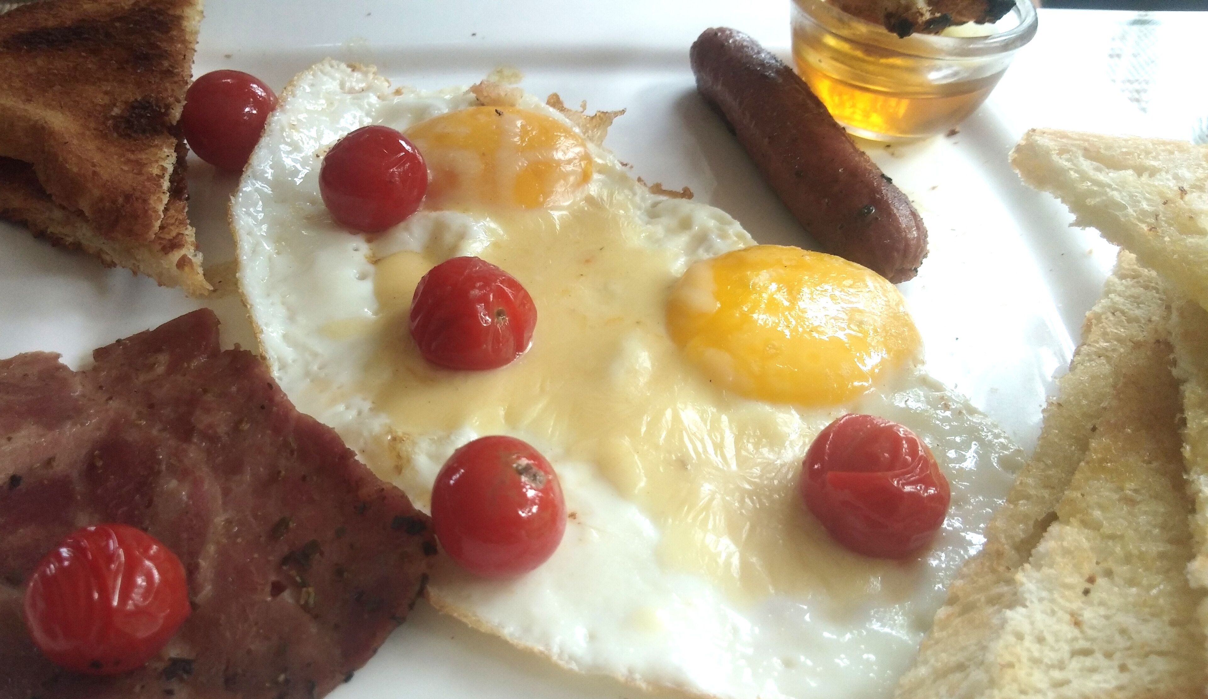 A breakfast plate with eggs, sausages, tomatoes, and toast.