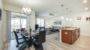 Un espace de vie moderne à aire ouverte comprenant une salle à manger, une cuisine et des portes-fenêtres coulissantes donnant sur un balcon.