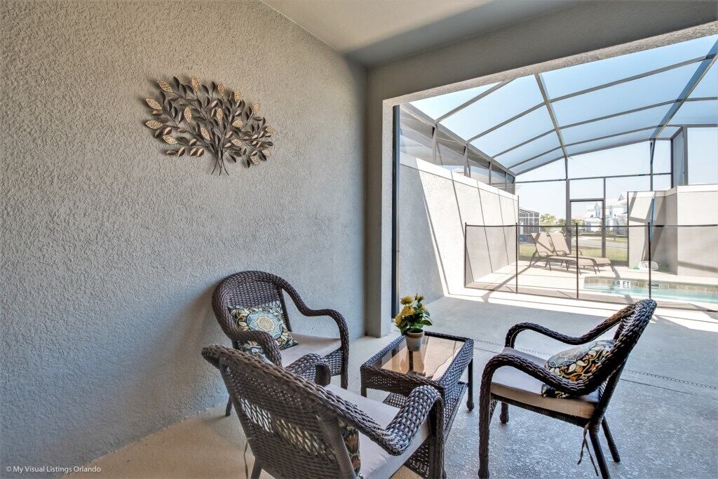 Un patio moderno con mobiliario de mimbre y cerramiento de vidrio.