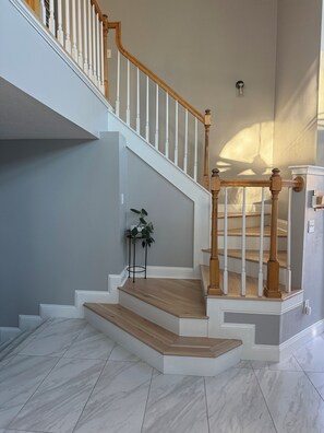 Un escalier avec des rampes en bois et un pot de fleurs placé sur le palier.