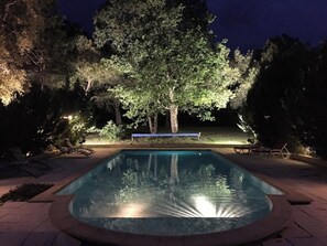Ein Pool, umgeben von Bäumen und Liegestühlen.
