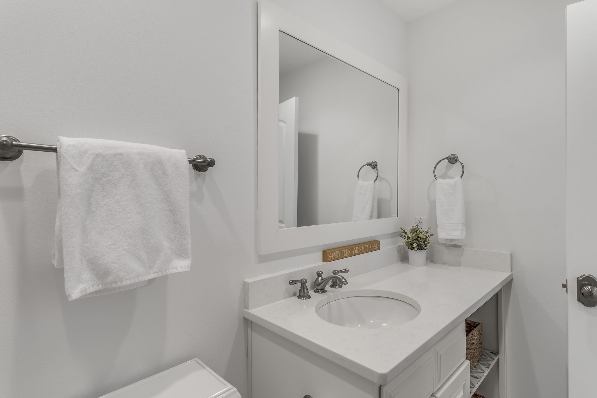 A bathroom with a white sink, a mirror, and two towels hanging on towel bars.