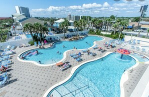 A large, multi-lane swimming pool with various water features and lounge areas.