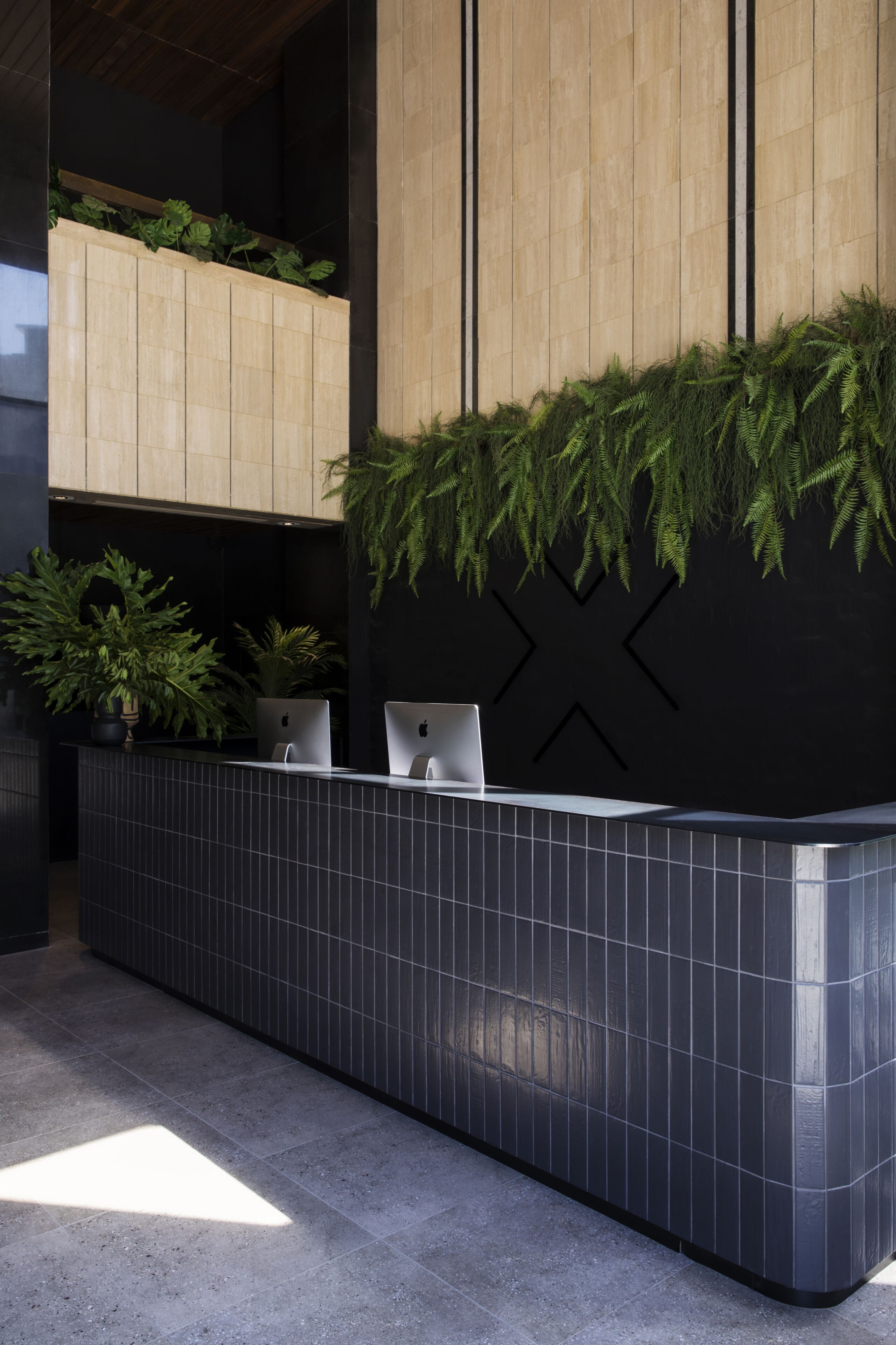 A reception desk with two Apple iMac computers, a potted plant, and a vertical garden.