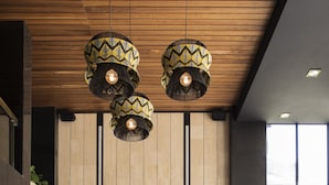 Un espace d’accueil moderne avec un plafond en bois, un comptoir d’accueil noir et des plantes vertes.