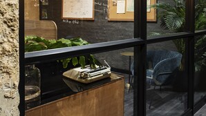 Un espace de bureau moderne avec un bureau en bois, un luminaire suspendu et un tableau d’affichage où sont accrochées des notes manuscrites et un schéma encadré.