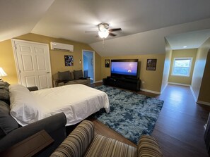 A spacious living room with a large bed, a TV, and a ceiling fan. - The Barndominium at Berkeley Ridge - Book your getaway today! (BERKELEY SPRINGS)