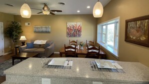 A dining area with a granite island, wooden chairs, and a table set for two. - The Barndominium at Berkeley Ridge - Book your getaway today! (BERKELEY SPRINGS)