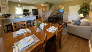 A spacious living room with a dining area, a kitchen, and a staircase leading to another level. - The Barndominium at Berkeley Ridge - Book your getaway today! (BERKELEY SPRINGS)