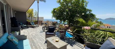 A balcony with wicker furniture, a pool, and a view of the sea.