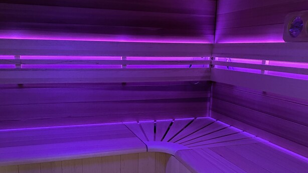 Una sauna con panche in legno e un catino di legno con un cucchiaio di legno.