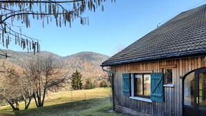 Una casa in legno con tetto in tegole, una piccola finestra con persiane e un vialetto lastricato.
