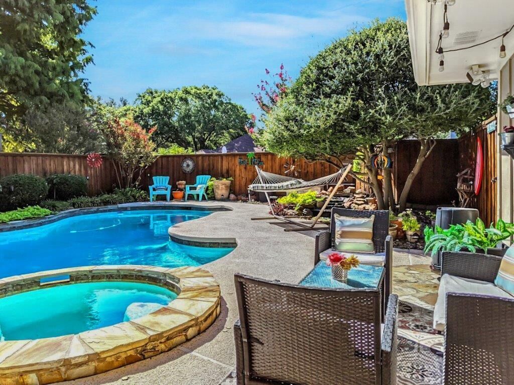 A backyard with a swimming pool, outdoor furniture, and a hammock.