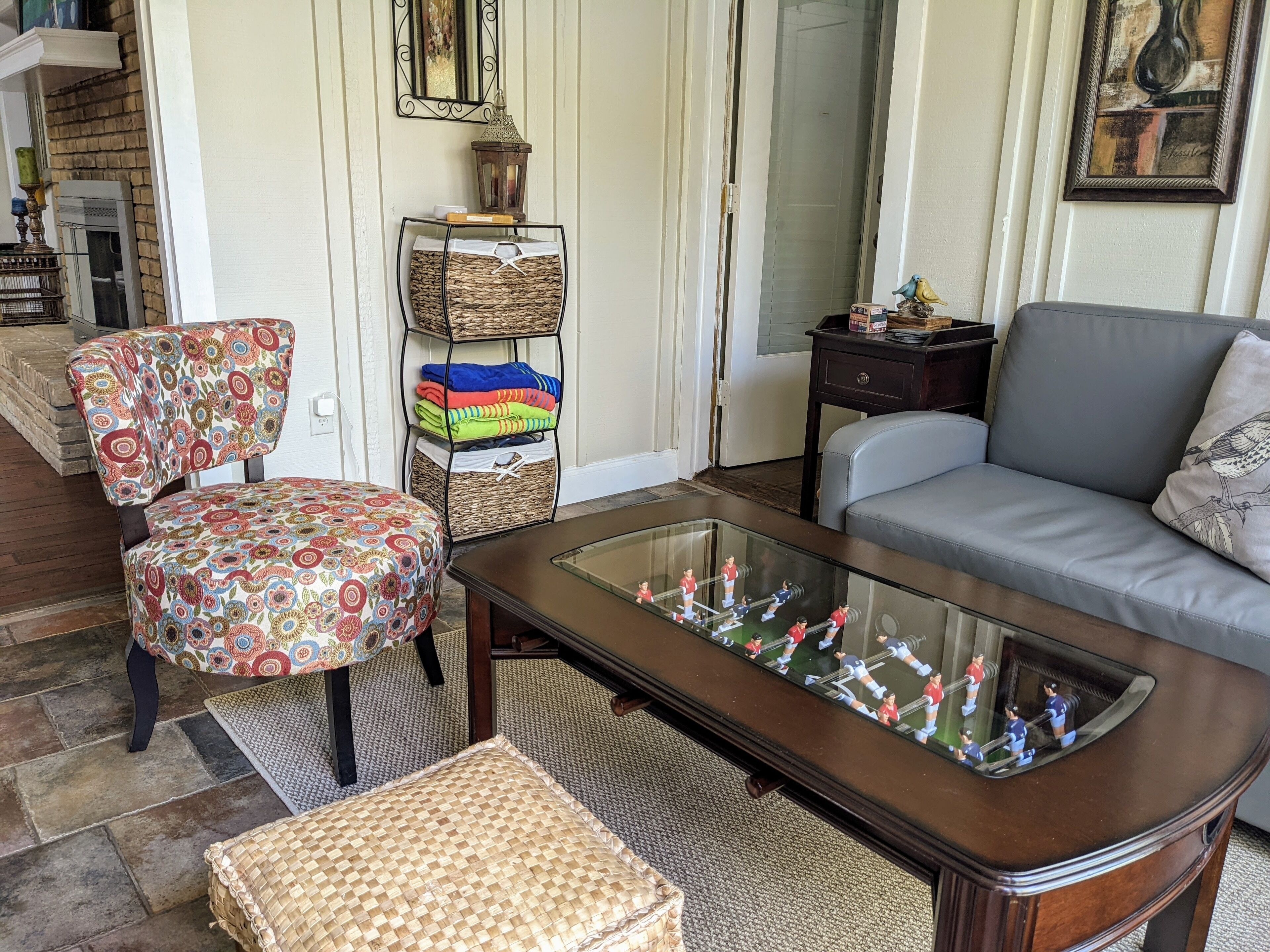 Un salon comprenant un canapé, un fauteuil et une table basse, avec un baby-foot.