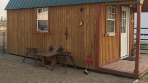A wooden cabin with a metal roof, a wooden door, and a small porch. - Cute Farmhouse Cottage  (Oakley)