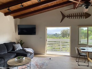 Un soggiorno moderno con un divano grigio scuro, un tavolino in legno e una grande decorazione a forma di pesce sulla parete.