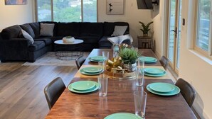 Un coin repas avec une table en bois dressée pour six personnes, entourée de chaises.