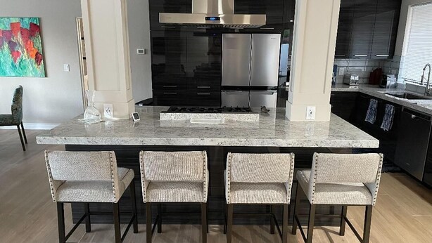 A modern kitchen with a large island, dark cabinetry, stainless steel appliances, and a colorful abstract painting on the wall. - Gorgeous Contemporary Palm Desert Home.  Ask about March - April discount!! (Palm Desert)