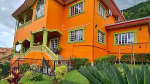 A two-story building with a bright orange facade, green window frames, and a small balcony. -  QBR Balcony Suite (St. Joseph)