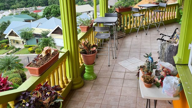 A balcony with green railings, potted plants, and a table with chairs. -  QBR Balcony Suite (St. Joseph)
