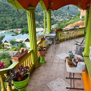 A balcony with green railings, potted plants, and a table with chairs. - QBR Balcony Suite (St. Joseph)